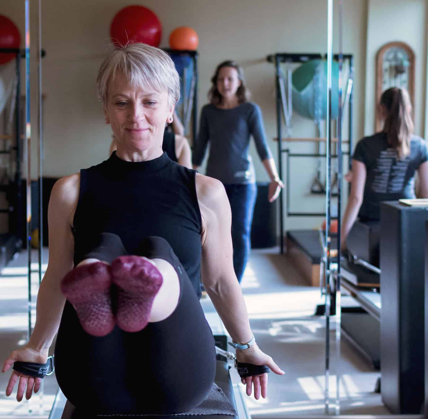 Laura Helsel, Pilates Process Owner, showed teaching a pilates class in a well lit studio, available in Toronto and Vancouver 