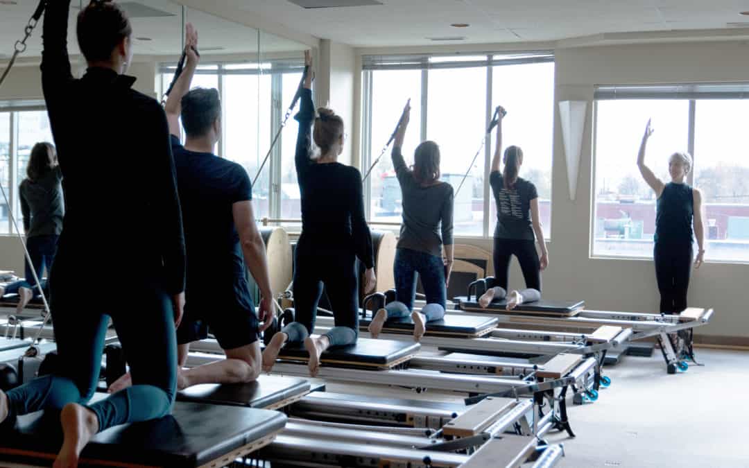 Pilates class using reformers in a well lit studio.