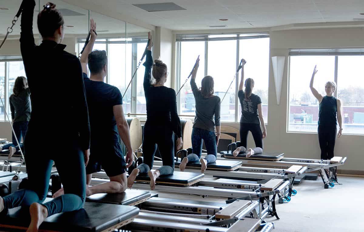 Pilates class using reformers in a well lit studio.